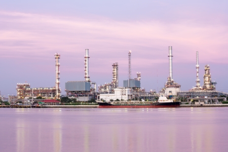 landscape of Oil refinery plant along river with tanker at duskのeditorial素材