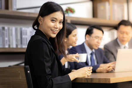 Portrait of confidence Businesswoman sit at table in meeting room in cafe with business team in background using for coporate background workの写真素材
