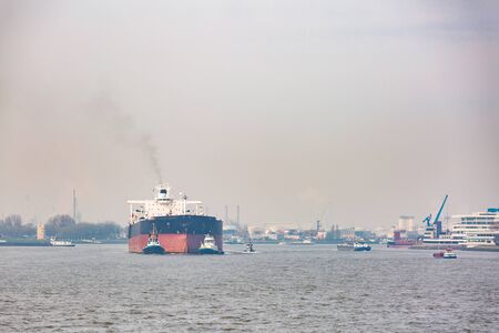 Big Cargo Containers Boat with Goods cargo Stack at the Pier docks port waiting for international sea freight transportation in Rotterdam Port of Netherlandsの写真素材