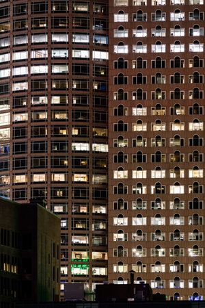 Late Working urban concept, window facade of business center office building at night, Boston, MA,...