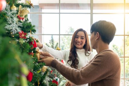 Young Teenager asian couple decorating Christmas tree together prepare for Christmas party holiday.の写真素材