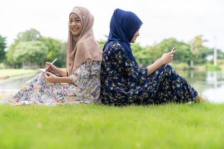 Young adult teenager Muslim Islamic Thai Asian women using smartphones and tablet in social media.の写真素材