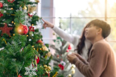 Christmas tree and ornament with background of young Teenager asian couple decorating Christmas tree together prepare for Christmas party holiday.の写真素材