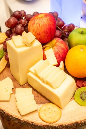 edam cheese with variety of fruit and cracker on wooden plate in buffet lineの写真素材