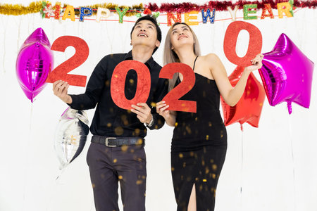 Young couple at a party holding red number of year 2020. Happy New Year celebration.