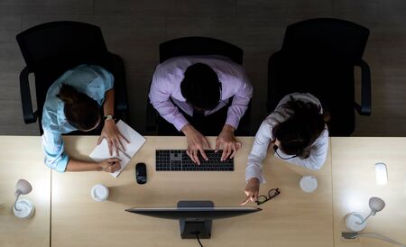 Late Night Environment, Top view of young adult friendly operator team with headsets discussing about customer case in a call center customer service and technical support. Using for 24 Hr. Call center Concept.の写真素材