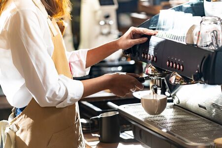 close-up shot of a barista brewing coffee by modern coffeemaker machine to making a cup of coffee with other barista working in background. Using for small business entrepreneur owner concept.の写真素材