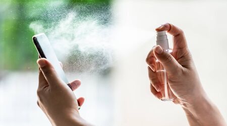 close-up cleaning mobile phone using alocohol spray from bottle spraying, disinfection for safety prevent and protect from infection of virus and germ Covid-19 coronavirus world pandemic.の写真素材