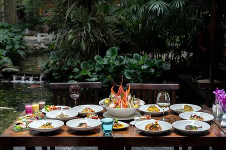 Side view premium variety of international food in garden of restaurant of lobster shrimp steak beef lamb pasta spaghetti risotto rice sushi sashimi and wine using for buffet food drink background.の写真素材