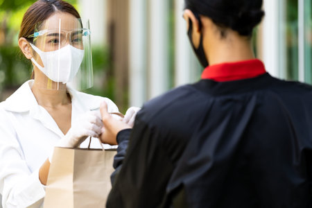 Portrait of atrractive asian woman give bakery grocery bag to delivery man to deliver it to customer...