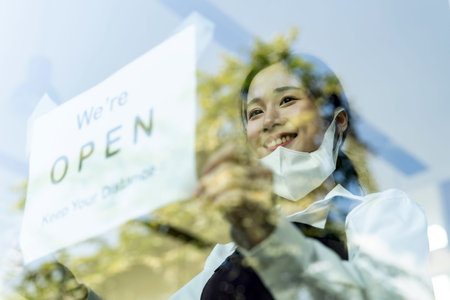 Asian female waitress putting on open signage with social distance for new normal restaurant. New...