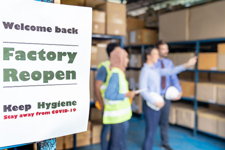 Factory reopen signage with warehouse manager and worker meeting in background after city lockdown...
