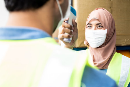 Islam asian warehouse worker take temperature to worker before getting in factory after reopening...