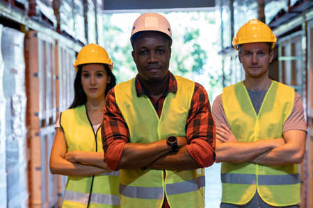 Portrait african black warehouse supervisor stand and crossed his arms with his interracial team in large warehouse distribution center. Business warehouse inventory logistic and teamwork conceptの写真素材