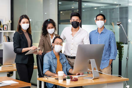 Group portrait of interracial business worker team wear protective face mask in new normal office with social distance practice prevent coronavirus COVID-19 spreadingの写真素材