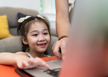 Asian girl elementary student using computer laptop for online learning and study from school while...