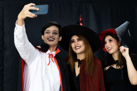 Group of friends asian young adult people celebrate a Halloween party carnival Festival. They wear Halloween costumes take selfie photographing. Halloween celebrate and international holiday concept.の写真素材