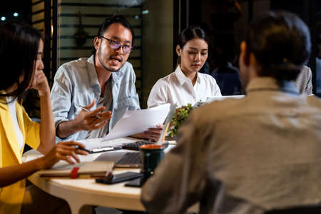Work late concept of Interracial asian business team brainstorm idea at office meeting room at night. Work hard deadline and overtime working and new business start up concept.の写真素材
