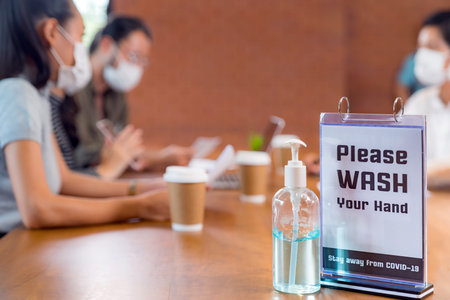 Signage of Hand sanitizer alcohol gel in meeting room with background of Asian team business people...