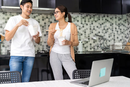 Asian couple work from home in the kitchen with delivery take away food while city lockdown from coronavirus covid-19 pandemic. New Normal lifestyle working from home.の写真素材