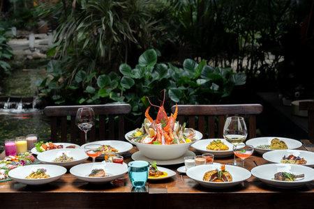 Side view premium variety of international food in garden of restaurant of lobster shrimp steak beef lamb pasta spaghetti risotto rice sushi sashimi and wine using for buffet food drink background.の写真素材
