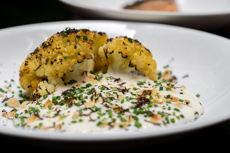Roasted Cauliflower with Parmesan and Hazelnut topping with spring onion and cauliflower soup, gourmet international cuisine recipe. Restaurant gastronomy food and drink consumerism concept.の写真素材