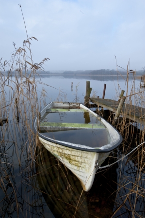 Abandoned boat at lake an misty november morningの写真素材