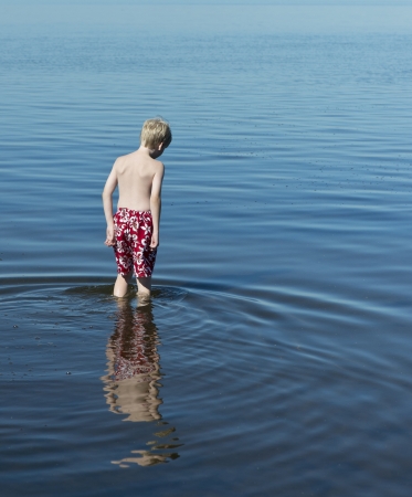 Young boy thinking about a swim in the oceanの写真素材
