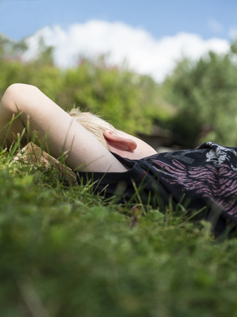 Young boy dreaming away while relaxing in the grassの写真素材