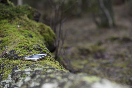 Cellphone lost or forgotten on a resting spot in natureの写真素材