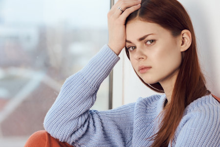 woman with sad expression sits by the window with a plaidの写真素材