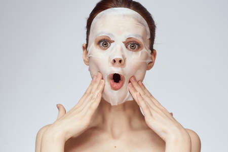 emotional woman cosmetic face mask close-up light backgroundの写真素材