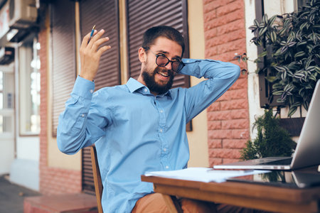 manager working in cafe with laptop outdoors