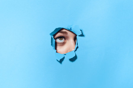 woman peeping through the holes in the poster blue studio background