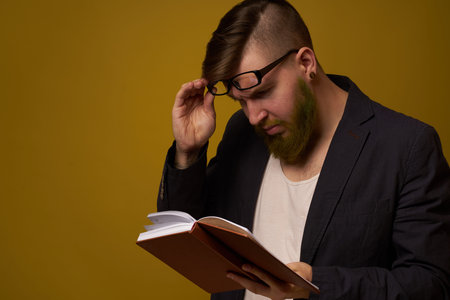 bearded man in a black jacket with a book in his hands education