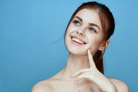woman with bared shoulders pigtail emotions posing blue backgroundの写真素材