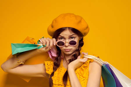 pretty woman with multicolored bags posing yellow backgroundの写真素材