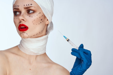 portrait of a woman in blue gloves syringe in hands contour on the face lifting studio lifestyleの写真素材