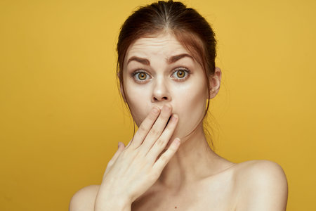 pretty woman naked shoulders and posing clear skin yellow background