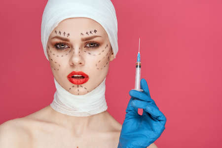 woman posing in blue gloves red lips surgery facial rejuvenation pink backgroundの写真素材