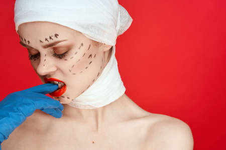 female patient posing in blue gloves red lips surgery facial rejuvenation isolated backgroundの写真素材