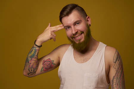 macho man in white t-shirt tattoos on his arms posing isolated backgroundの写真素材