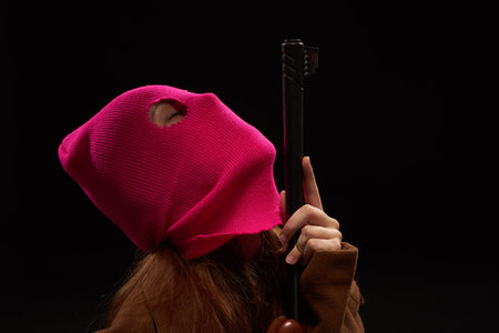 woman in glamorous pink mask shotgun posing black background