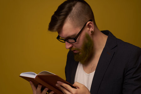 bearded man in a black jacket with a book in his hands education
