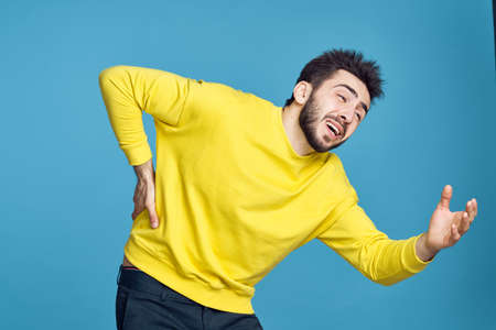 man in yellow sweater health problems emotions blue backgroundの写真素材
