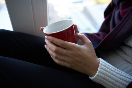 woman near window with red cup depression close-upの写真素材