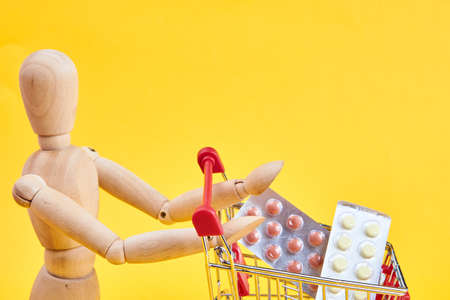 wooden dummy with medicine cart yellow backgroundの写真素材
