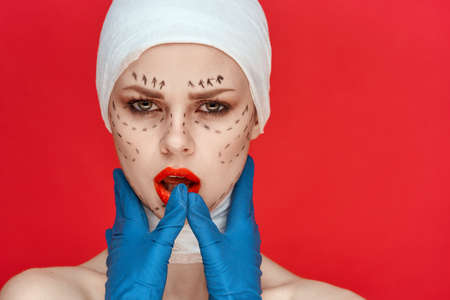 a person in blue gloves syringe in hands contour on the face lifting close-upの写真素材