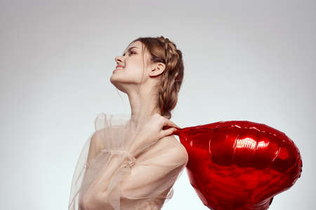 cheerful woman red heart in the hands of the balloon isolated backgroundの写真素材
