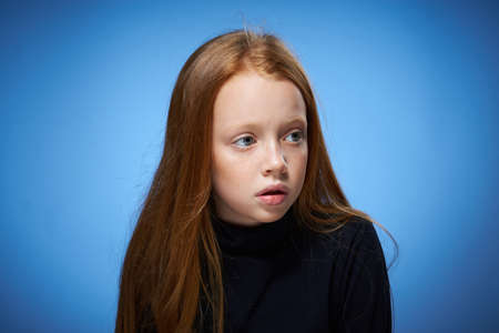 redhead girl with freckles on her face posing close-up blue backgroundの写真素材